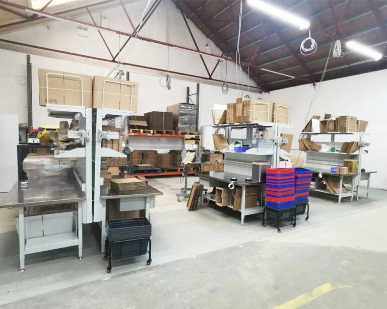 Packaging warehouse with packing workstations, paper cushioning machine, and material trolleys
